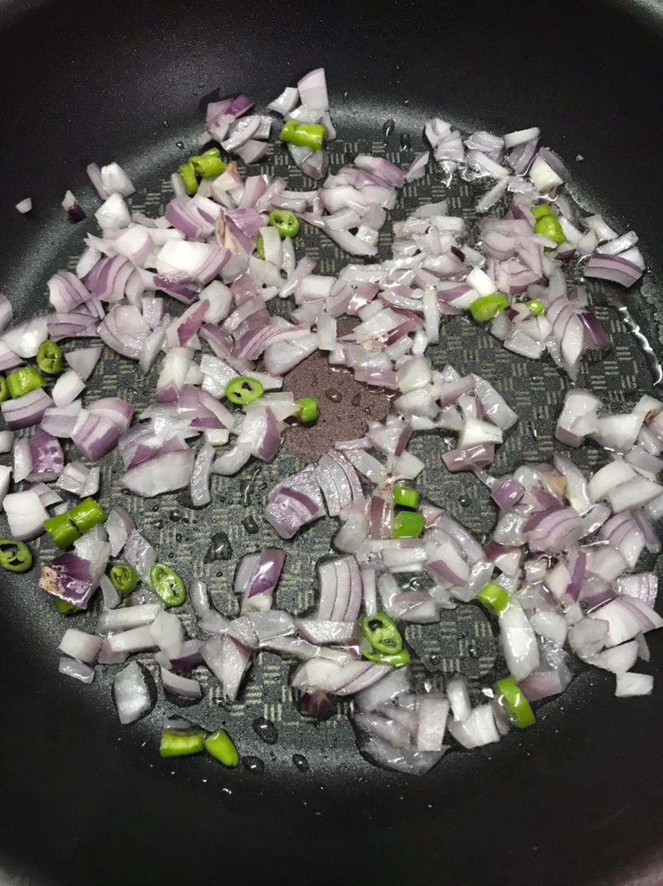 chopped onions and green chilies sautéing in a pan