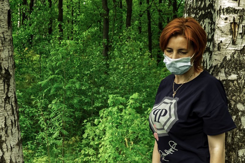 A woman wearing mask standing around trees