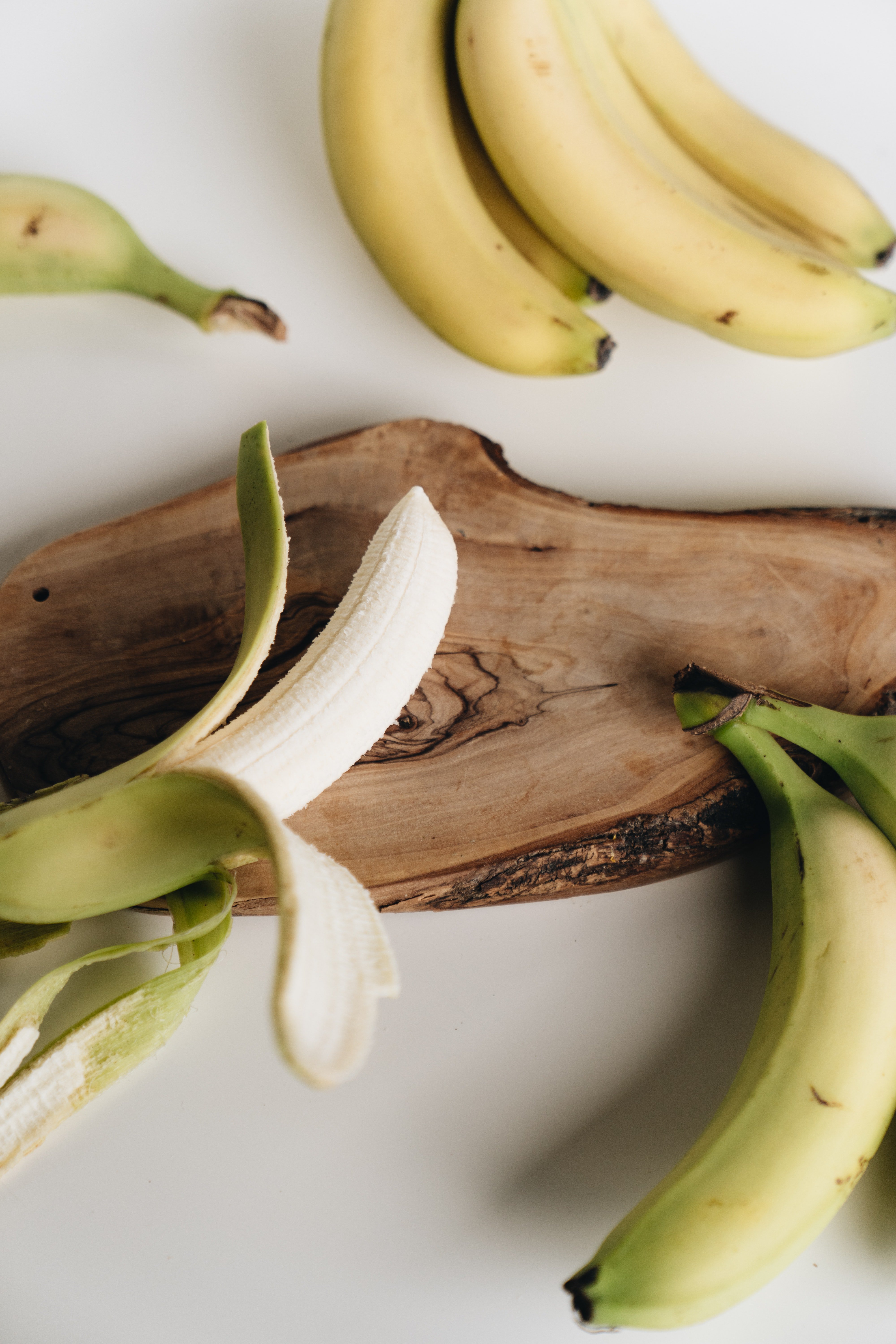 A peeled banana and a bunch of bananas on a slab