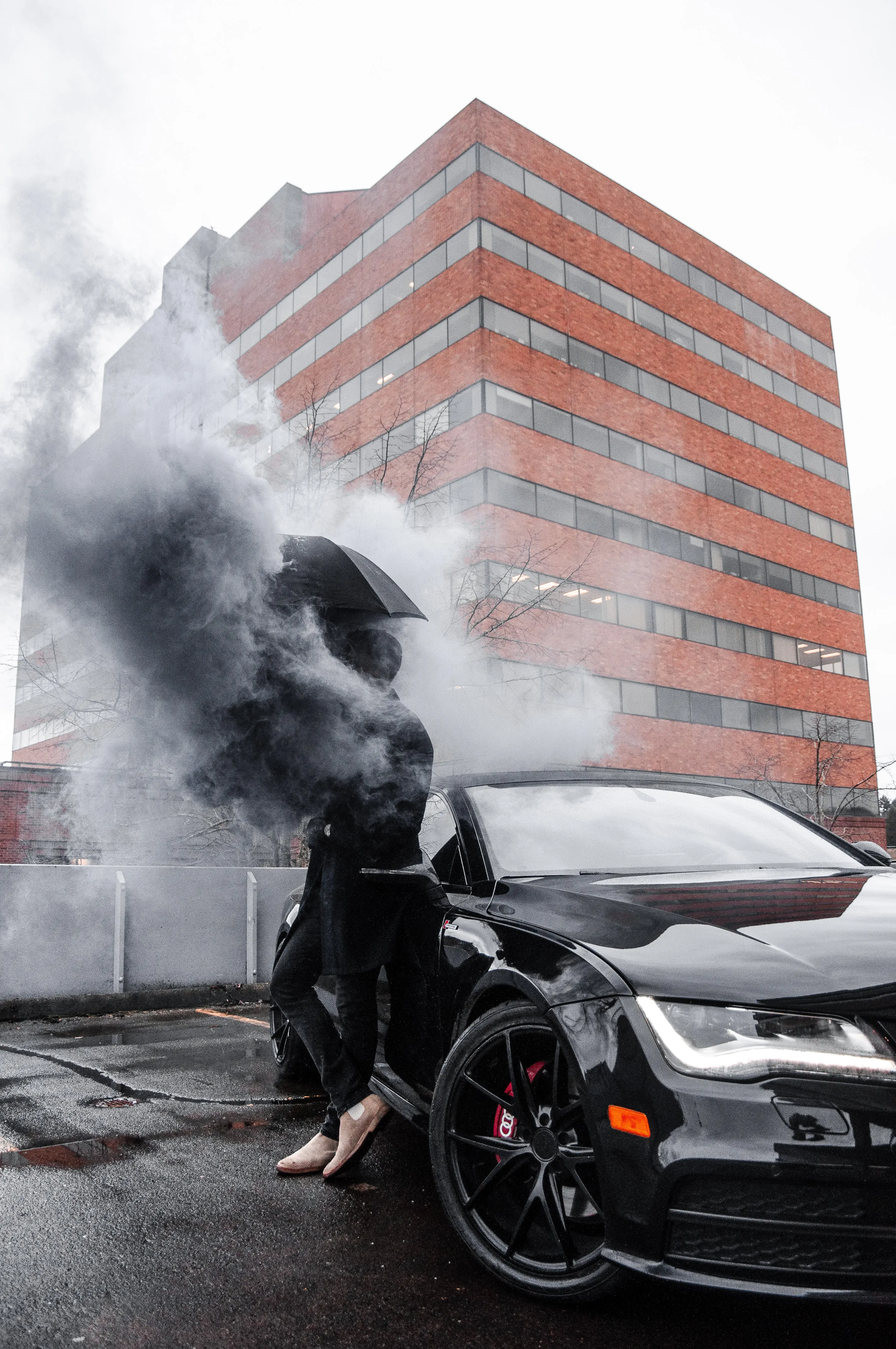 A man standing in front of a car and a lot of smoke coming