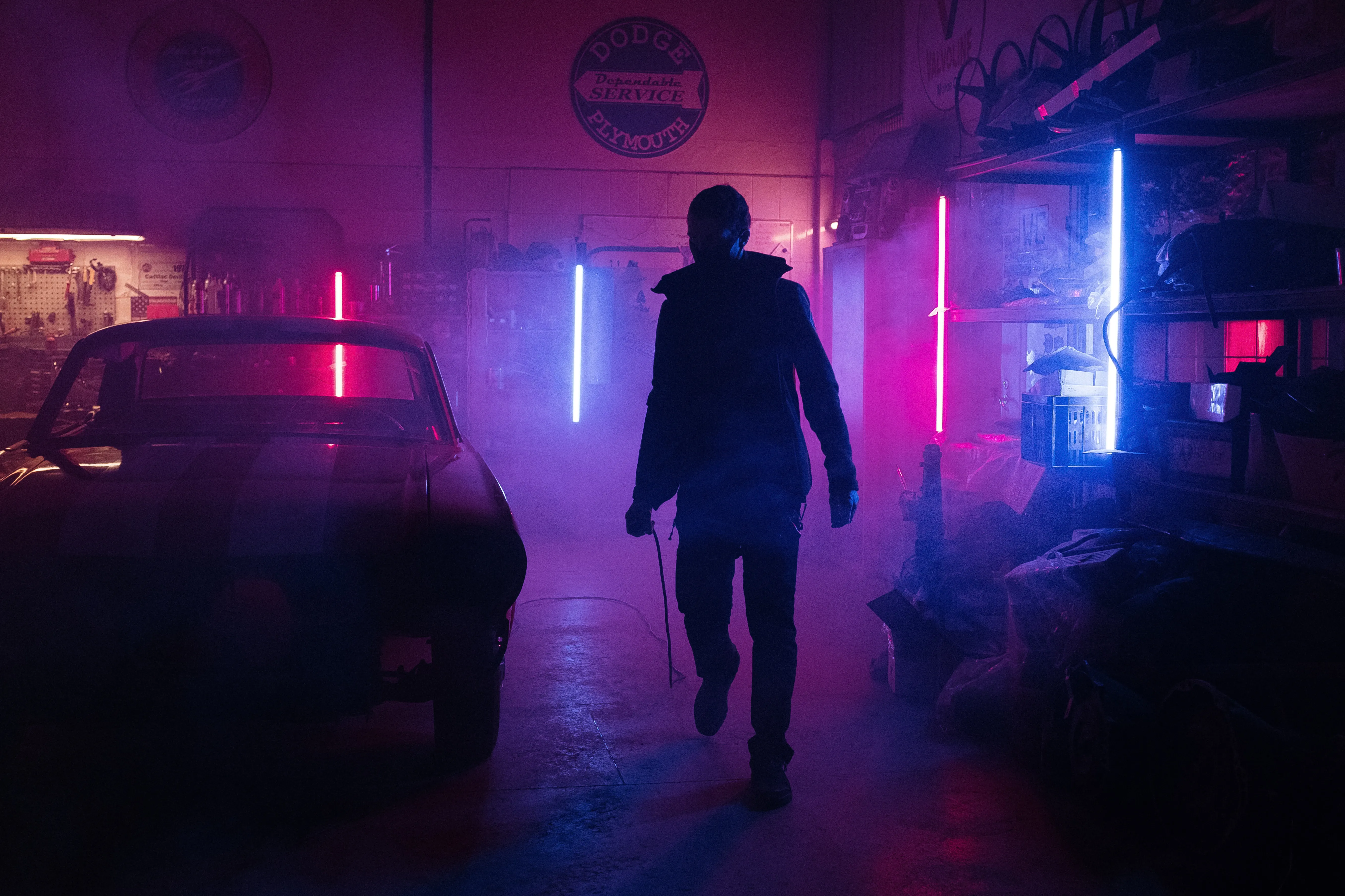 A man standing in pink purple lights with a car