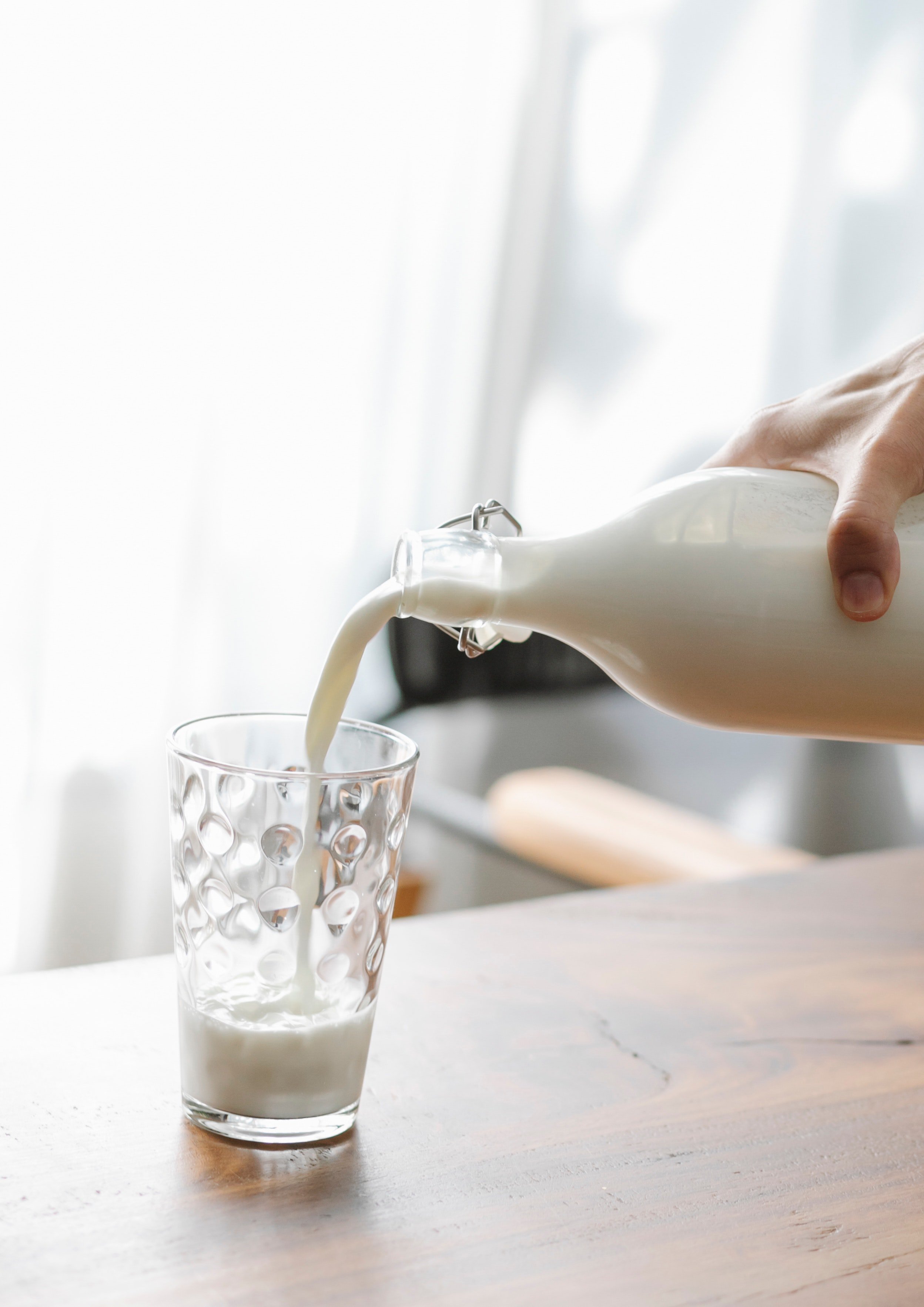 A person pouring milk in a glass from a bottle