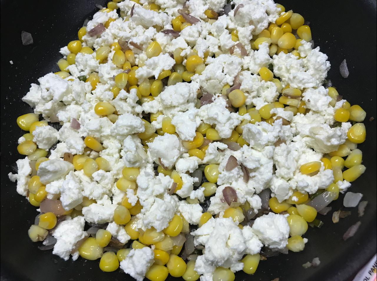crumbled paneer added to corn and onion in the pan
