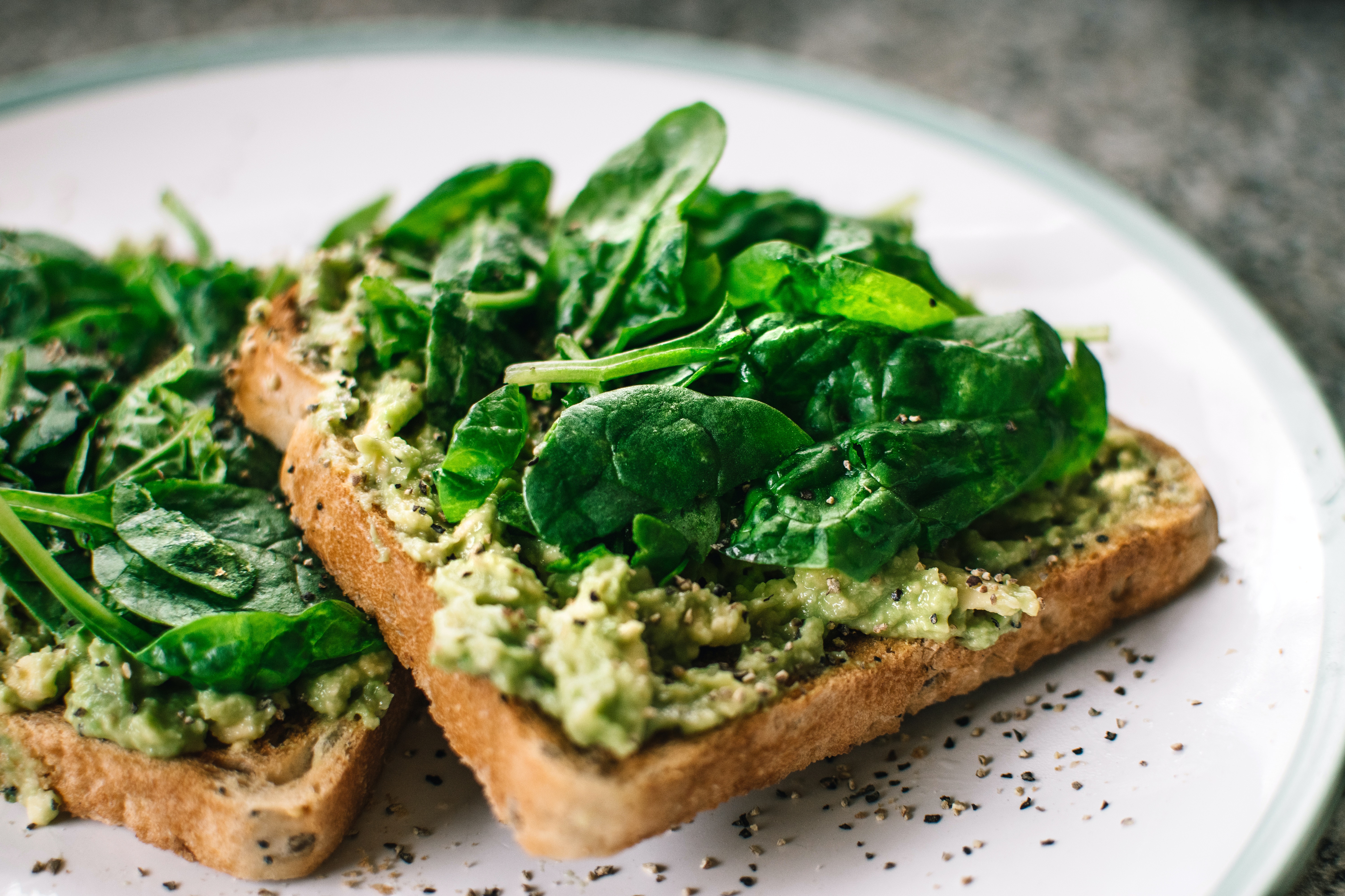 two toasts with greens and sauce on top