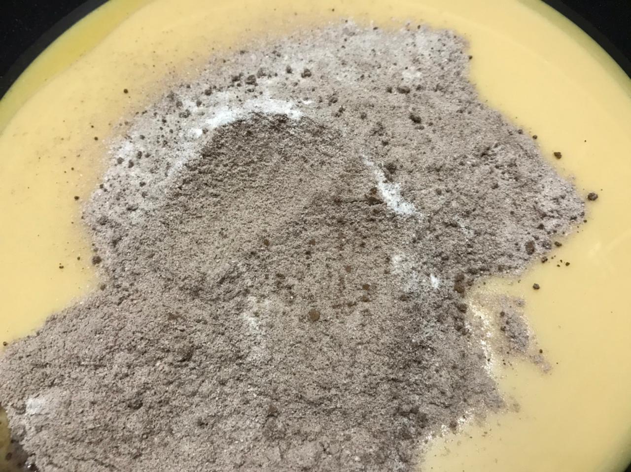 Adding the cocoa powder and milk powder mix to condensed milk in a pan