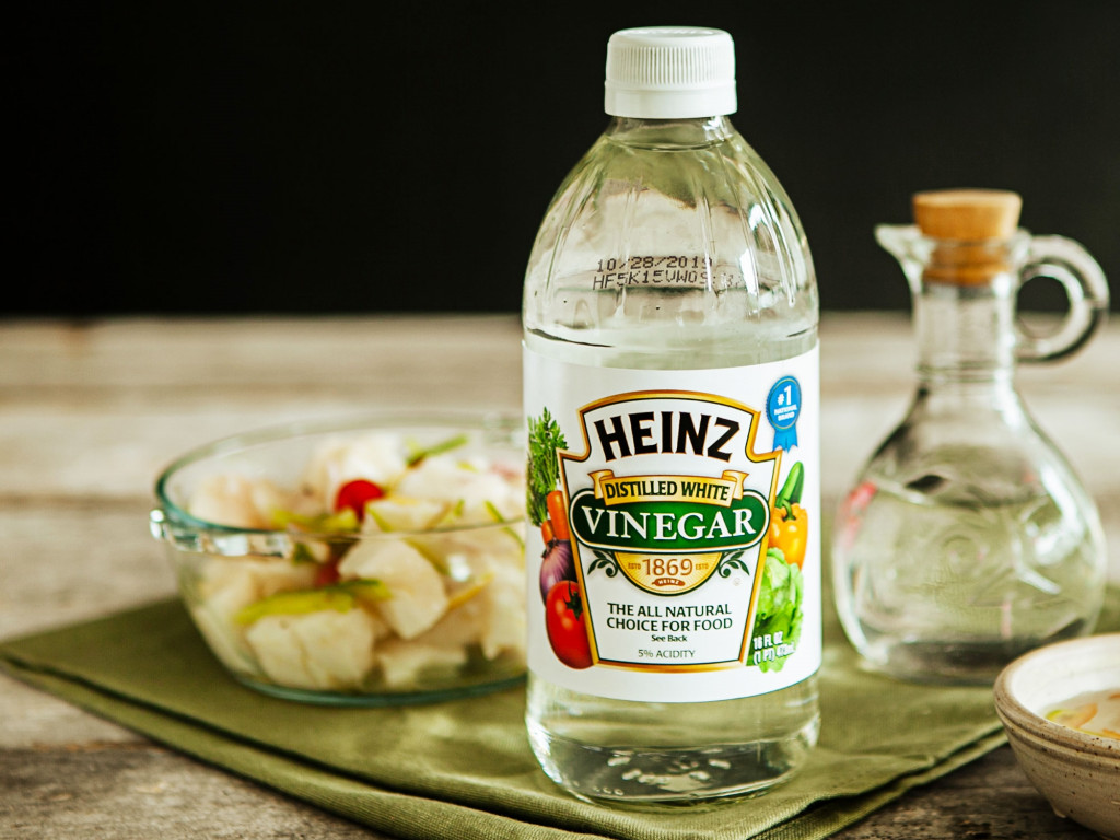 a bottle of vinegar with a bowl of salad
