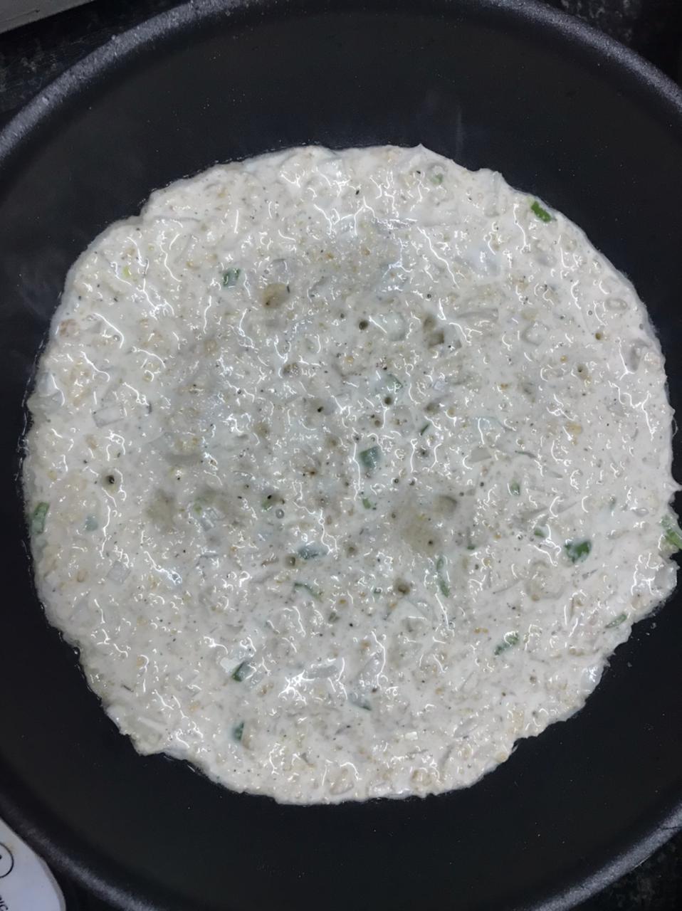 Spreading oats chilla batter on a pan