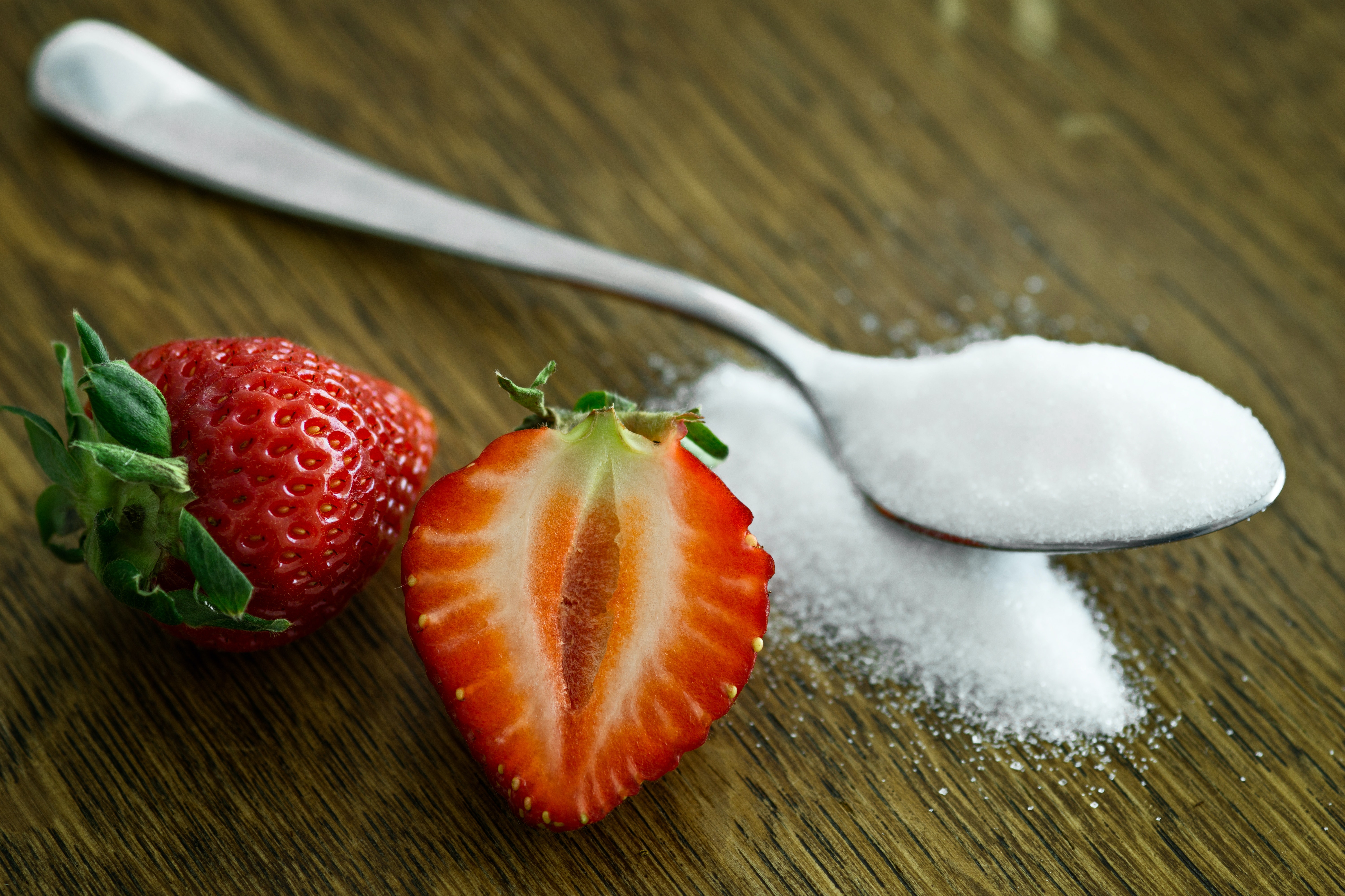 strawberries and spoon of sugar on a table