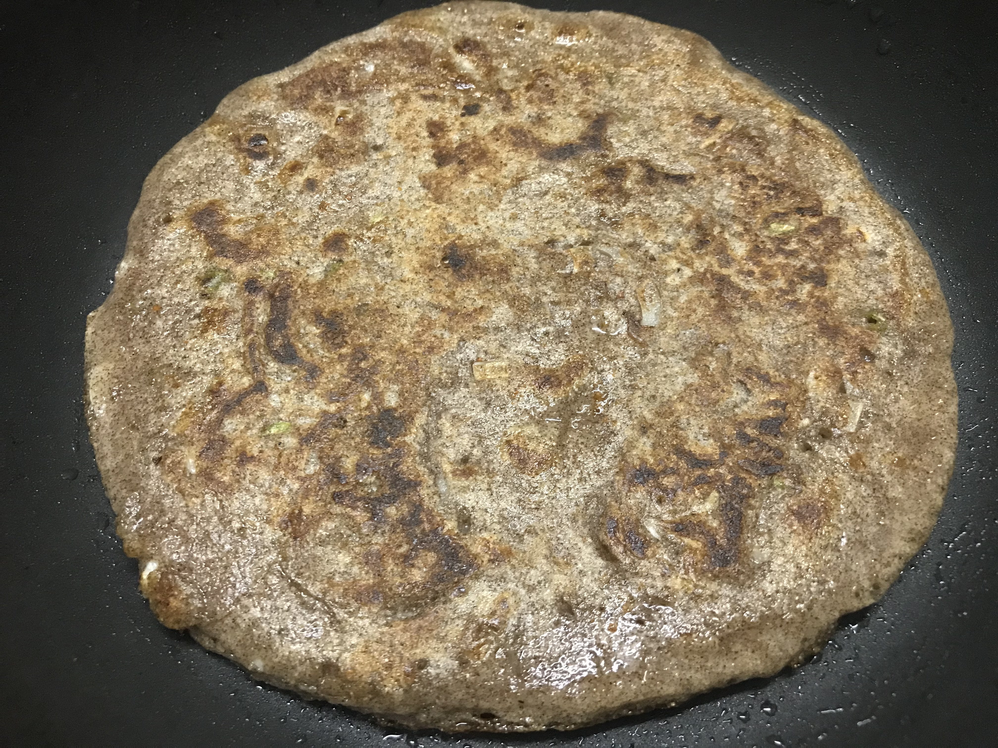 Flipping ragi chilla to other side and cooking it from both sides