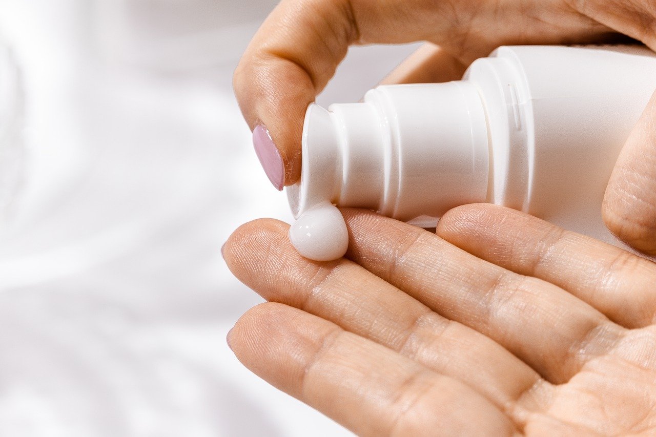 A lady taking a pea sized moisturizer in her palm