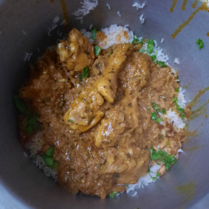 marinated chicken, rice, coriander and fried onions in a container