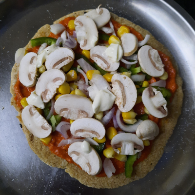 adding sauce and veggies to pizza base
