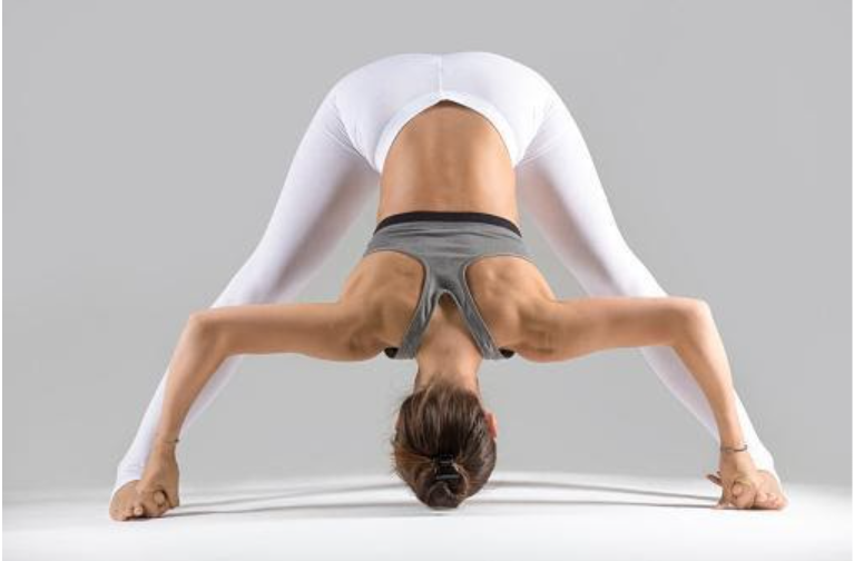 A female on Yoga mat in yoga position Prasarita Padottanasana (Wide-Legged Standing Forward Bend)
